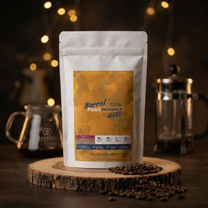 Puede incluir: Una bolsa blanca vertical de granos de café Takaraa Barrel Aged Pearl con sabor a whisky. La etiqueta presenta patrones geométricos dorados, el texto 'Barrel Aged', '0% Alcohol' y 'Specialty Coffee beans', con una tabla de detalles.