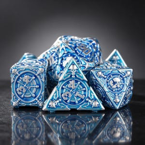 May include: A set of metallic polyhedral dice featuring a bright blue and silver finish. The dice are intricately detailed with nautical motifs, including ship wheels, anchors, and skull emblems. Each face displays raised numbers and symbols.