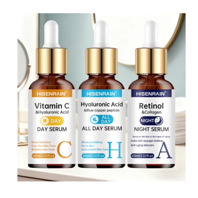 May include: Three amber glass dropper bottles labeled HISENRAIN. The left bottle is a Vitamin C & Hyaluronic Acid Day Serum, the center is a Hyaluronic Acid & Blue Copper Peptide All Day Serum, and the right is a Retinol & Collagen Night Serum.