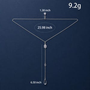 K&ouml;nnte beinhalten: Eine silberfarbene Lariat-Halskette mit einem blumenf&ouml;rmigen Kristallanh&auml;nger, einem kleinen runden Kristallakzent und einem tropfenf&ouml;rmigen Kristallanh&auml;nger. Die Kettenl&auml;nge betr&auml;gt 66 cm, mit einem 3,5 cm Anh&auml;nger, 16,5 cm Verl&auml;ngerung und 9,2g Gewicht.