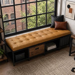 May include: A long rectangular storage bench featuring a tufted tan faux leather cushion seat, a black metal frame, an open shelf, and a central wooden drawer with a black handle. The unit provides multiple compartments for organization and storage.