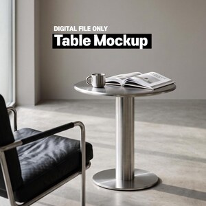 Op de afbeelding: Een ronde tafel van geborsteld metaal met een centrale cilindrische voet. Op de tafel staan een metalen mok en een open boek. De tekst "DIGITAL FILE ONLY Table Mockup" wordt weergegeven in het bovenste gedeelte van de afbeelding boven de tafel.