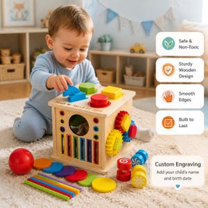 May include: A wooden activity cube featuring a shape sorter top, colorful gears, and vertical slots. The cube is engraved with the name Noah and the date March 12, 2021. It includes various loose wooden shapes, sticks, and discs in red, blue, green, and yellow.