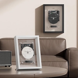 May include: Two framed CoolGeek displays featuring disassembled hard drive components mounted on a circuit board. One display has a white frame with a white disk, and the other has a black frame with a black disk, both under glass.