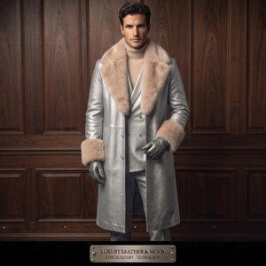 Può includere: Un lungo cappotto color argento metallizzato con un ampio colletto in pelliccia beige e polsini abbinati, indossato sopra un dolcevita beige e un abito argento doppiopetto. Il completo include guanti argento. Una targa recita: LUXURY LEATHER & WOOL - ETHICAL LUXURY - SILVER & SKIN.