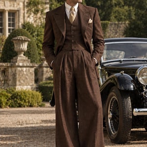 Può includere: Un abito a tre pezzi marrone composto da una giacca, un gilet abbottonato e pantaloni larghi con pieghe. L'outfit include una camicia bianca con colletto, una cravatta color marrone chiaro, un fazzoletto da taschino e scarpe eleganti in pelle marrone scuro.