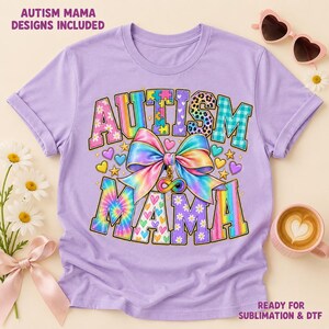 Pode incluir: Uma t-shirt roxo-claro com o texto AUTISM MAMA em letras de bloco coloridas e estampadas. Um grande la&ccedil;o multicolorido com efeito tie-dye e um s&iacute;mbolo de infinito encontra-se no centro. O design inclui pequenos cora&ccedil;&otilde;es e estrelas.