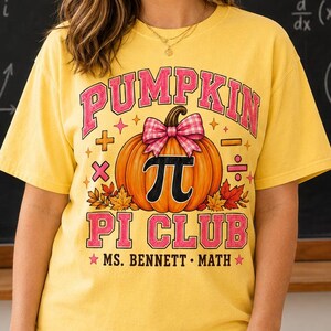 May include: A yellow short-sleeve t-shirt featuring a graphic of an orange pumpkin with a pink plaid bow and the mathematical symbol for pi. The text reads PUMPKIN PI CLUB and MS. BENNETT MATH, surrounded by small math symbols and autumn leaves.