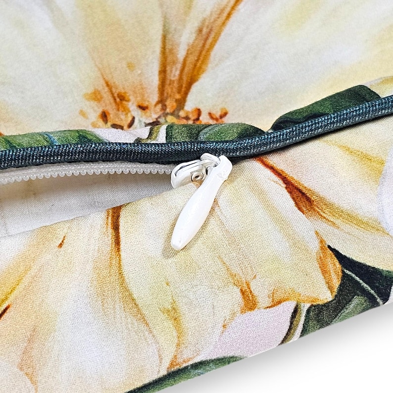 Peut inclure: Une housse de coussin en tissu avec un imprim&eacute; floral &agrave; grande &eacute;chelle dans des tons cr&egrave;me, jaune et vert. La housse pr&eacute;sente un passepoil vert fonc&eacute; et une fermeture &eacute;clair invisible blanche avec une tirette blanche centr&eacute;e sur la couture.