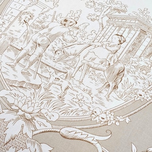 Puede incluir: Una tela beige con un estampado toile de jouy marr&oacute;n. El dise&ntilde;o muestra a una persona junto a una fuente, una persona montando a caballo, un perro peque&ntilde;o y columnas cl&aacute;sicas. La escena est&aacute; enmarcada por un borde ovalado con motivos florales.