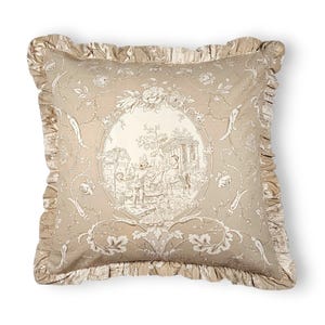 Puede incluir: Un coj&iacute;n cuadrado de tela beige claro con un estampado toile de jouy marr&oacute;n oscuro. El centro presenta un medall&oacute;n ovalado que representa una escena pastoral con figuras y arquitectura, rodeado de motivos florales y un borde con volantes.