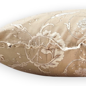 Puede incluir: Un coj&iacute;n rectangular con una base de tela marr&oacute;n claro y un patr&oacute;n floral y de enredaderas en marr&oacute;n oscuro. El coj&iacute;n incluye un detalle de borde con volantes en el lateral, confeccionado con la misma tela estampada que el cuerpo.