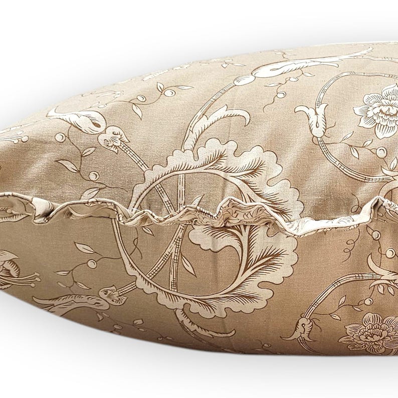 Puede incluir: Un coj&iacute;n rectangular con una base de tela marr&oacute;n claro y un patr&oacute;n floral y de enredaderas en marr&oacute;n oscuro. El coj&iacute;n incluye un detalle de borde con volantes en el lateral, confeccionado con la misma tela estampada que el cuerpo.