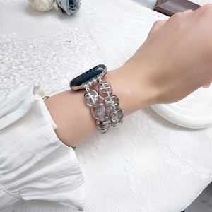 May include: A smartwatch band featuring two parallel strands of translucent, smoky gray, square-shaped beads. The band connects to a black smartwatch face via silver-toned metal hardware, creating a layered, bracelet-style appearance on the wrist.