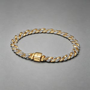 Könnte beinhalten: Ein Gliederarmband in Gold- und Silberoptik mit abwechselnd polierten goldfarbenen Gliedern und silberfarbenen Gliedern, die mit kleinen klaren Steinen besetzt sind. Das Armband hat einen rechteckigen goldfarbenen Verschluss mit der Gravur Pandora.