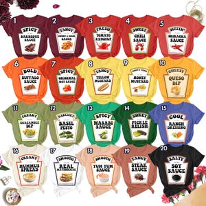 May include: A collection of twenty t-shirts in various colors, each featuring a graphic print of a condiment bottle label with text such as Spicy Barbeque Sauce, Tangy Sweet & Sour Sauce, Fresh Tomato Ketchup, and other food-themed designs.