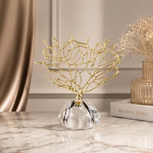 Peut inclure: Une sculpture décorative composée d'une structure en forme de corail doré, montée sur une base en verre transparent arrondie. La pièce en métal présente un design ajouré complexe avec de fines branches entrelacées s'étendant vers le haut.
