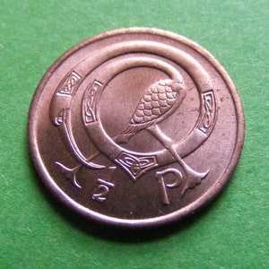 May include: A copper-coloured Irish 2 pence coin featuring a bird standing on a Celtic knot design. The coin has the inscription "2p" on the bottom.
