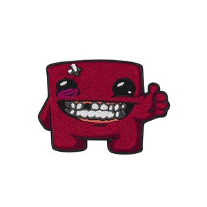 May include: A red embroidered patch featuring a square-shaped character with a black outline. The character has large black eyes, a wide mouth with visible teeth, a small white bandage on its head, and a hand giving a thumbs-up gesture.