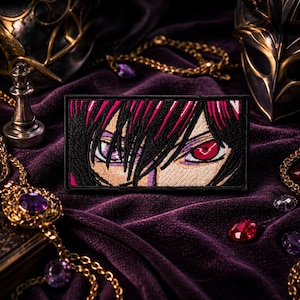 May include: A rectangular embroidered patch featuring a close-up illustration of a character's face with dark hair, one purple eye, and one glowing red eye. The patch has a black border and is rendered in vibrant thread colours against a dark fabric.