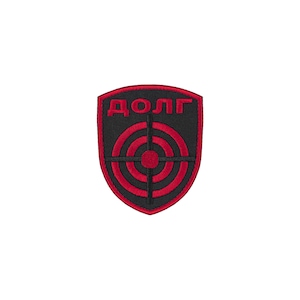 May include: A shield-shaped embroidered patch featuring a black background with a red border. The design includes a red circular target graphic with crosshairs and the Cyrillic text "ДОЛГ" in red lettering positioned at the top of the patch.