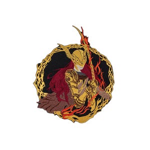 May include: A circular embroidered patch featuring a warrior figure in gold armor with a winged helmet and long red hair. The figure holds a long staff surrounded by stylized orange and red flames, all enclosed within a decorative gold border.