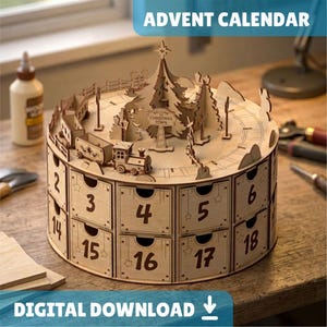 May include: A circular wooden advent calendar featuring numbered drawers from 2 to 18. The top surface displays a laser-cut Christmas town scene with a central tree, a train, and a sign reading Welcome to Christmas Town. The structure is light-colored wood.