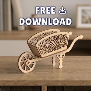 May include: A light-colored wooden wheelbarrow-shaped decorative object featuring intricate laser-cut scrollwork and bird motifs on the side panels. The text FREE DOWNLOAD with a download icon is positioned above the wooden structure.
