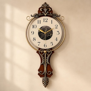 May include: A wall clock featuring a circular face with black Arabic numerals on a cream background, a central black marble-patterned inlay, and gold-toned hands. The frame is dark brown wood with ornate gold metal accents and a pendulum.