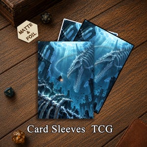 May include: Two rectangular card sleeves featuring a blue-toned underwater scene with a large skeletal sea creature, submerged ruins, and a small figure holding a light. A hexagonal token with the text MATTE & FOIL is visible nearby.