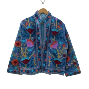 May include: A blue long-sleeve jacket featuring an open front and a mandarin collar. The garment is decorated with vibrant, multi-colored floral embroidery in shades of red, pink, orange, and light blue, set against a solid blue fabric base.