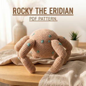 Pode incluir: Uma criatura de crochê bege com seis pernas e pequenos pontos bordados em azul-petróleo. O texto acima do objeto diz ROCKY THE ERIDIAN PDF PATTERN. A criatura tem um corpo arredondado e é feita de fio com uma textura de ponto visível.