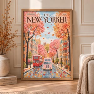 Könnte beinhalten: Ein gerahmter Kunstdruck, der ein Cover des New Yorker Magazins vom 14. Oktober 1985 zeigt. Die Illustration stellt eine Stadtstraße im Herbst mit roten und rosafarbenen Bussen, buntem Herbstlaub an den Bäumen und Blättern auf der Straße dar.