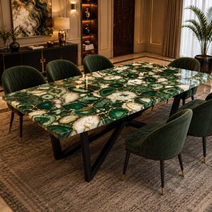 May include: A rectangular dining table featuring a polished green agate gemstone slab top with natural white and dark green banding, supported by a black metal frame, surrounded by six dark green upholstered chairs with black metal legs.
