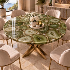 May include: A round dining table featuring a tabletop made of polished green agate slices with natural crystalline patterns, supported by a gold-toned metal base with an X-shaped design, surrounded by four upholstered beige chairs.