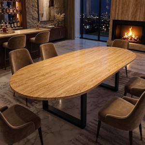 Pode incluir: Uma mesa de jantar oval com um tampo de pedra texturizada em bege claro e uma base de metal preto, rodeada por seis cadeiras estofadas num tom castanho suave. A superfície da mesa apresenta veios naturais e um acabamento liso.