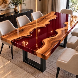 Puede incluir: Una mesa de comedor rectangular con un tablero de madera de borde natural y un río de resina de color rojo intenso en el centro. La mesa se apoya sobre dos patas de metal negro en forma de U y está rodeada de varias sillas tapizadas en beige.