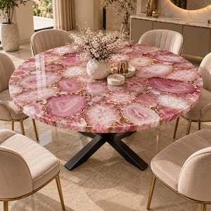 May include: A round dining table featuring a tabletop composed of polished pink agate slices with natural crystalline patterns, supported by a black metal X-shaped base, surrounded by four upholstered chairs with gold-toned metal legs.