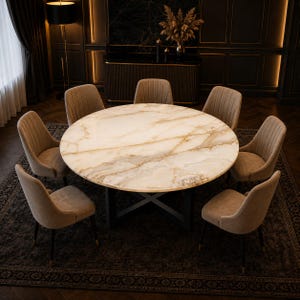 Puede incluir: Una mesa de comedor redonda con tablero de mármol pulido en tonos crema y oro sobre una base de metal negro en forma de cruz, rodeada de siete sillas tapizadas en color beige con costuras verticales y patas negras con detalles dorados.