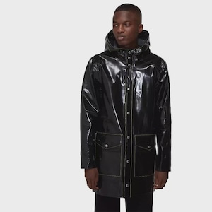 Puede incluir: Un impermeable negro brillante y resistente al agua con capucha, cierre frontal de botones con broches de metal plateado y dos grandes bolsillos delanteros con solapa. La chaqueta presenta costuras visibles a lo largo de las costuras.