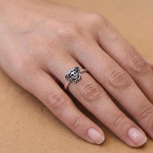 Op de afbeelding: Een zilverkleurige metalen ring met een gedetailleerd leeuwenkopontwerp als middelpunt. De ring heeft een gepolijste afwerking met donkere, verdiepte delen om de gelaatstrekken van de leeuw, inclusief de manen en de snuit, te benadrukken.