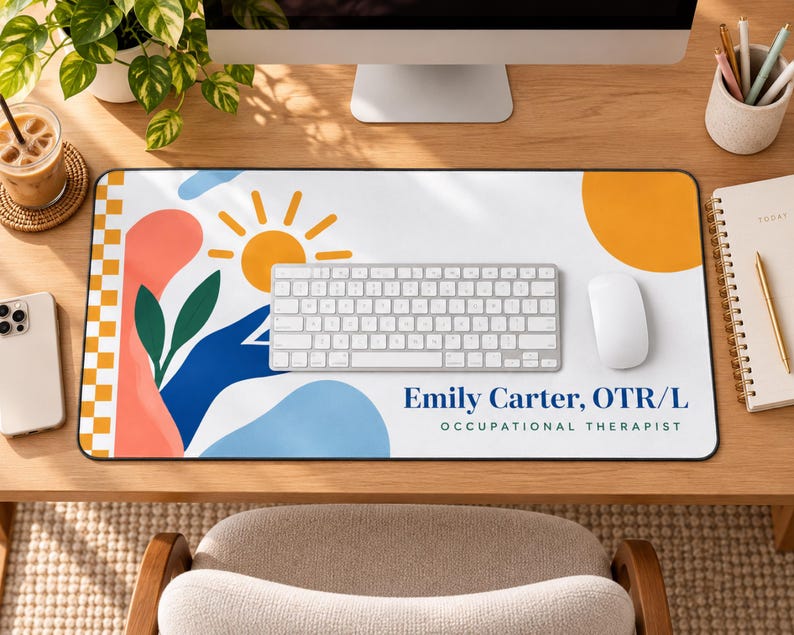 Op de afbeelding: Een rechthoekige bureaumat met een witte achtergrond en abstracte vormen in koraal, blauw en geel, inclusief een zon- en bladgrafiek. De tekst luidt Emily Carter, OTR/L OCCUPATIONAL THERAPIST in donkerblauwe en zwarte letters.