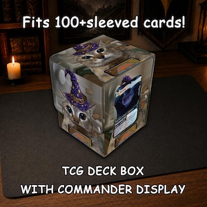 May include: A square TCG deck box with a commander display, featuring a graphic of a cat wearing a purple wizard hat with yellow stars. The box displays the text Fits 100+sleeved cards!, TCG DECK BOX, and WITH COMMANDER DISPLAY on the image.