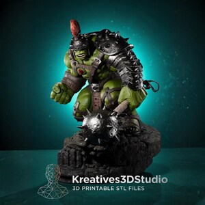 May include: A green muscular humanoid figurine wearing a silver spiked helmet with a red crest and dark metal armor. The figure holds a large spiked mace and stands on a dark rocky base. Text at the bottom reads Kreatives3DStudio 3D PRINTABLE STL FILES.