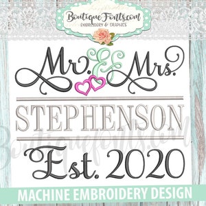 Op de afbeelding: Machine borduurontwerp met de tekst "Mr. & Mrs. Stephenson Est. 2020" in een cursief lettertype met twee roze harten. De tekst is in grijs en zwart met een lichtgrijze lijn eronder.
