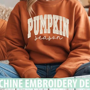 Peut inclure: Un sweat-shirt à manches longues orange brûlé avec le texte PUMPKIN season en police universitaire blanche. Le mot PUMPKIN est en lettres capitales, tandis que season est en écriture cursive. Le vêtement a un col rond et des poignets côtelés.