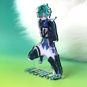 May include: An acrylic standee featuring an anime-style character with teal hair, red eyes, and a dark blue and white outfit. The character is in a kneeling pose, mounted on a clear rectangular base with a printed pattern of blue and white squares.