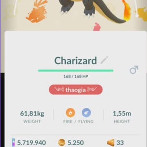 Może przedstawiać: Cyfrowy wyświetlacz czarnej postaci Charizard w żółtych goglach, ze statystykami obejmującymi 3091 CP, 168 HP, wagę 61,81 kg i wysokość 1,55 m. Ekran pokazuje ikony typu ognistego i latającego, liczbę cukierków oraz przycisk megaewolucji.