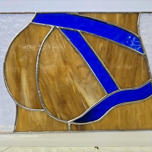 May include: A rectangular stained glass panel featuring a composition of tan, marbled glass segments separated by thin metal solder lines. The design includes bold, curved strips of vibrant cobalt blue glass and textured, translucent white glass.