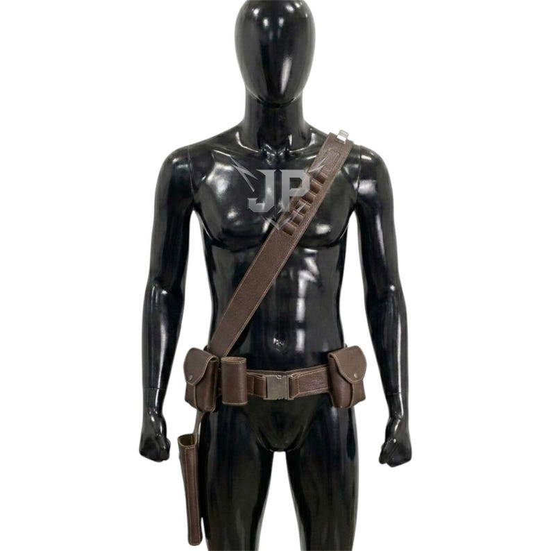 May include: A brown leather utility belt and shoulder strap set worn on a black mannequin. The gear includes a waist belt with a metal buckle, two side pouches, a holster, and a shoulder strap featuring multiple loops for small cylindrical items.